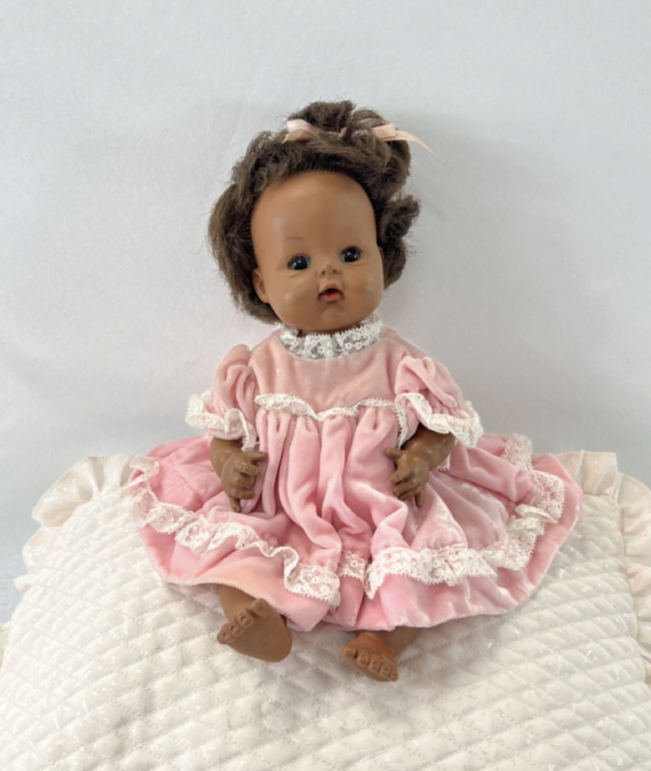 "1965 Madame Alexander Pinky doll in pink dress with lace trim and brown curly hair with bow"